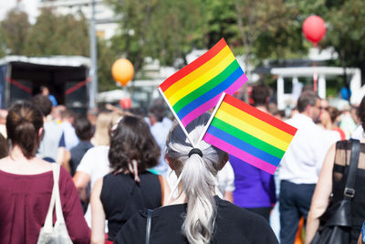 Rear view of woman with rainbow flags in hair on street