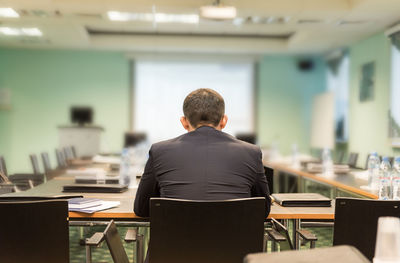 Rear view of businessman sitting at board room