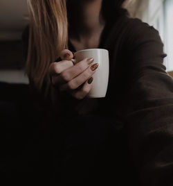 Midsection of woman holding coffee cup