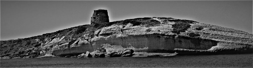 Rock formation on beach against clear sky