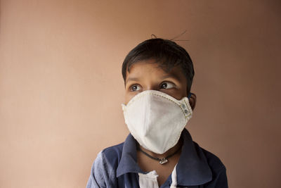 Close-up of smiling boy wearing mask against wall