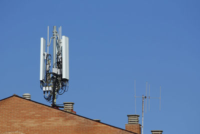 Low angle view of telecommunication tower on roof against sky