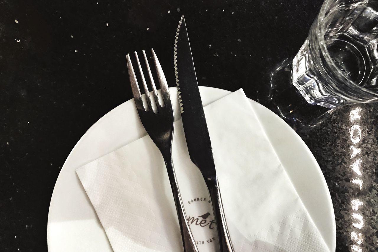 CLOSE-UP OF FORK AND PLATE ON TABLE IN MIRROR