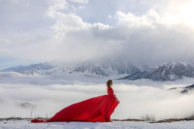 Rear view of woman standing on snow covered mountain