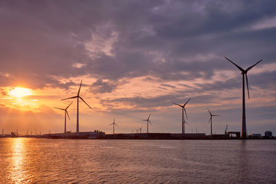 Wind turbines in antwerp port on sunset.