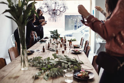 Multi-ethnic female colleagues are photographing various perfume bottles on table at workshop