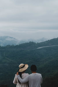 Rear view of man looking at mountains against sky