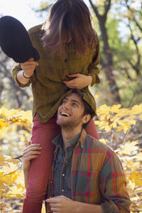 Young woman playfully sitting on her boyfriend's shoulders