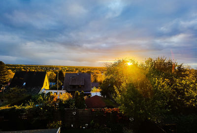 Trees and buildings against sky during sunset