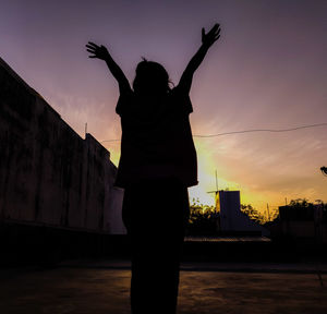 Rear view of silhouette woman standing against sky during sunset