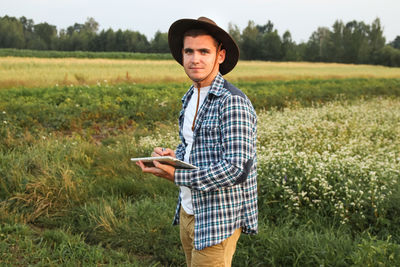 A farmer amidst a verdant wheat field, holding a tablet, symbolizing smart farming. agronomist