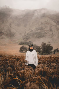 Woman standing on mountain with expression heart touching