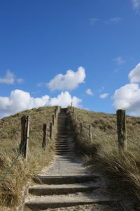 Wooden posts on field against sky