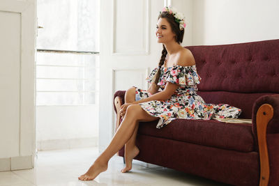 Young woman sitting on sofa at home