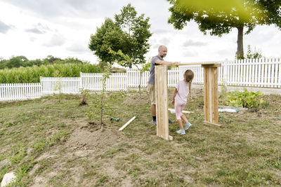 Father making raised with with daughter playing in garden