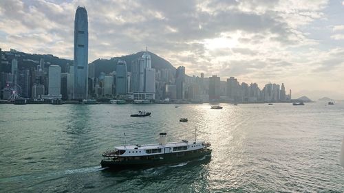 Nautical vessel on sea by buildings against sky in city