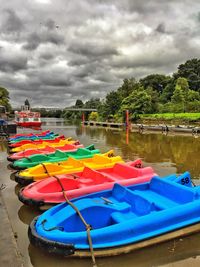 Multi colored boats moored on river against sky