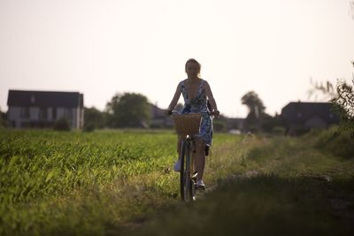 Rear view of man riding bicycle on field