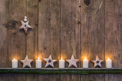 Star ornaments and lit candles on wooden wall