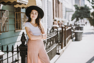 Portrait of beautiful young woman standing against wall