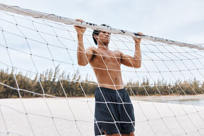 Rear view of woman standing against chainlink fence