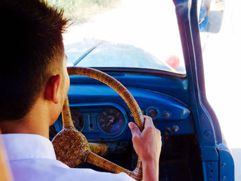 Rear view of man driving car on street