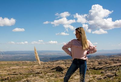 Thoughtful woman standing on mountain against blue sky