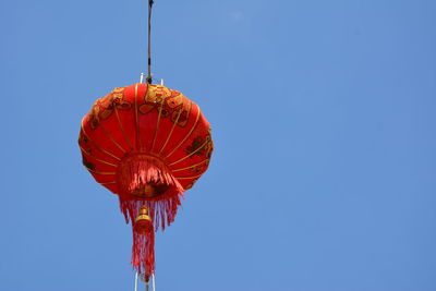 Low angle view of lanterns hanging against clear blue sky