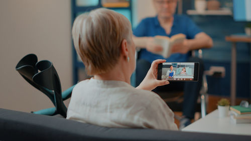 Rear view of woman doing video call on smart phone