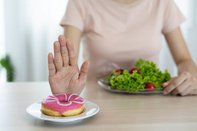 Midsection of woman holding ice cream in plate on table