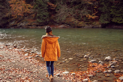 Rear view of man standing on shore during autumn