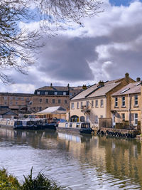 Buildings by river against sky