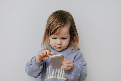 Portrait of cute girl holding gift against white background