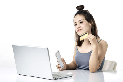 Young woman using smart phone against white background