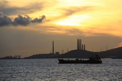 Boats sailing in sea at sunset