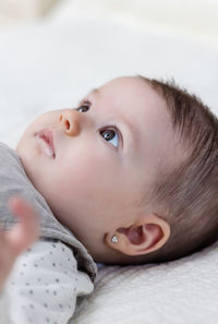 Portrait of cute baby girl lying on bed