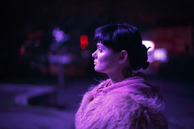 Portrait of woman looking at illuminated during winter at night