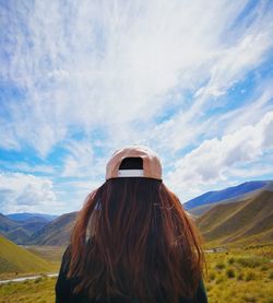 Rear view of woman photographing on field against sky