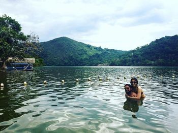 Portrait of friends in lake against sky