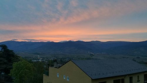 Houses and mountains against sky during sunset