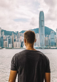 Rear view of man in city against sky