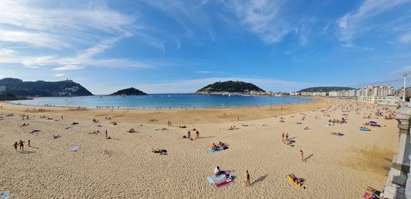 Panoramic view of people on beach against sky