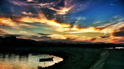 Scenic view of lake against dramatic sky during sunset