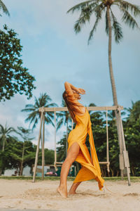 Low section of young woman standing on palm tree