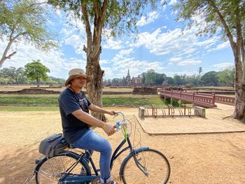 Man sitting on bicycle against sky