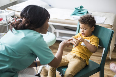 Female pediatrician pointing at arm of boy in hospital