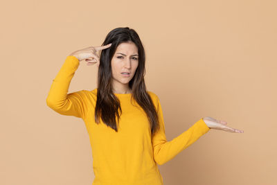 Young woman standing against yellow background