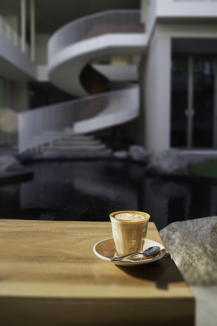 COFFEE CUP ON TABLE AGAINST CAFE