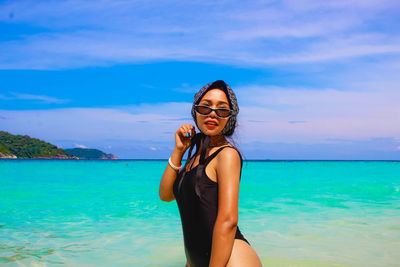 Woman standing at beach against blue sky