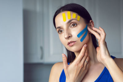 Portrait of a young woman with pasted konesiotape for rejuvenation and face tightening